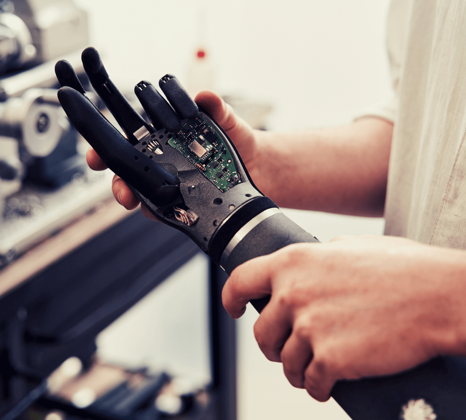 Close up of a pair of hands holding a black, robotic arm.