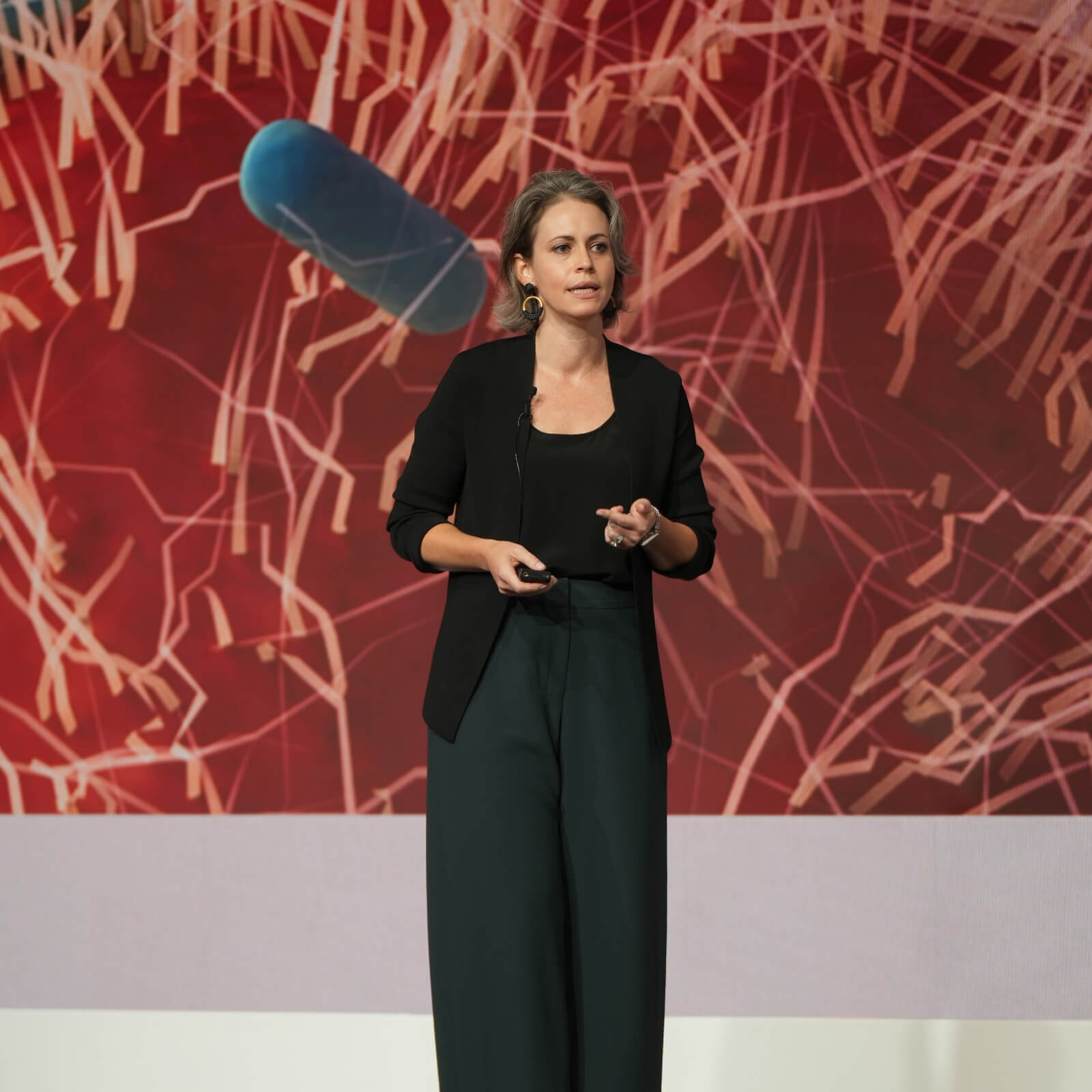 Megan Frisk presenting on stage in front of a large screen