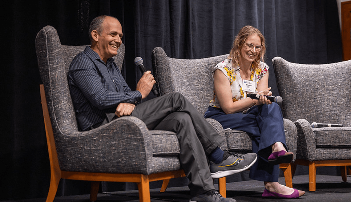 Two scientists sit on chairs and speak into microphones.